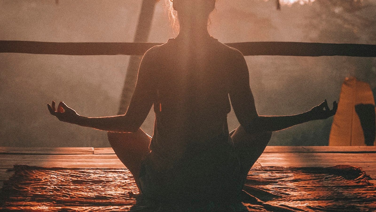 Person meditating at sunrise on a misty mountaintop